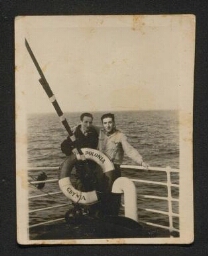 Photographie de deux hommes sur un navire, en mer, devant la bouée 