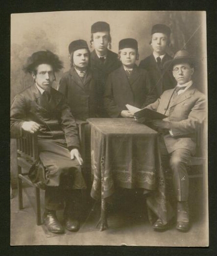 Photographie d'un Juif religieux et d'un Juif laïc attablés, quatre enfants juifs entre eux