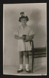 Photographie d'une petite fille en robe blanche, avec un ruban dans les cheveux, non datée