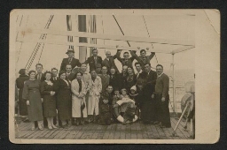Photographie d'un groupe de personnes posant sur le navire en mer devant la bouée indiquant 