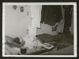 Jeune homme travaillant, couché sur un grabat