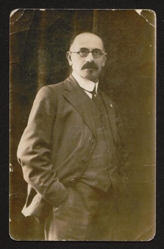 Photographie d'un homme en costume, cravate, lunettes rondes et moustache, non datée