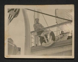 Photographie d'un homme accoudé au rebord du navire devant une bouée indiquant 