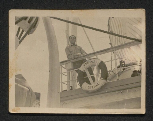 Photographie d'un homme accoudé au rebord du navire devant une bouée indiquant "Polonia-Cdynia", non datée