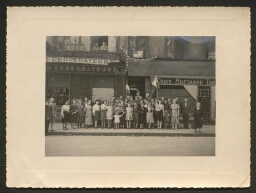 Photographie d'un groupe de personnes posant avec un écriteau indiquant "Les rescapés du 87 rue du Temple, le 24 août 1944"