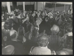 Photographie d'un homme coiffé d'un chapeau noir, prononçant un discours au micro devant une assemblée sur une terrasse, non datée